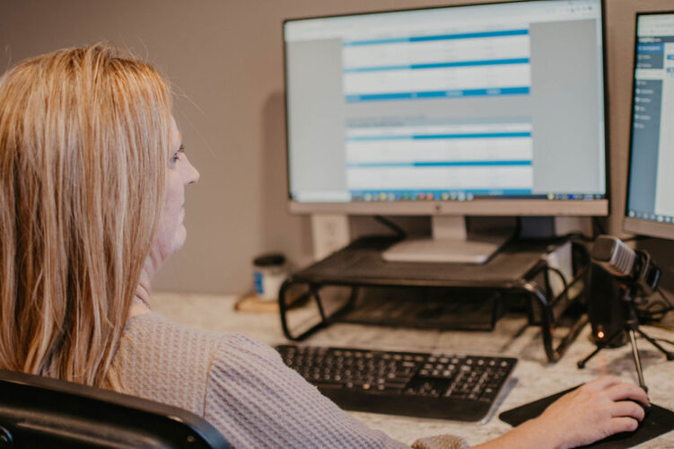 Janet Rippe working at a computer managing a seedstock customer database and sale catalog mailing list.
